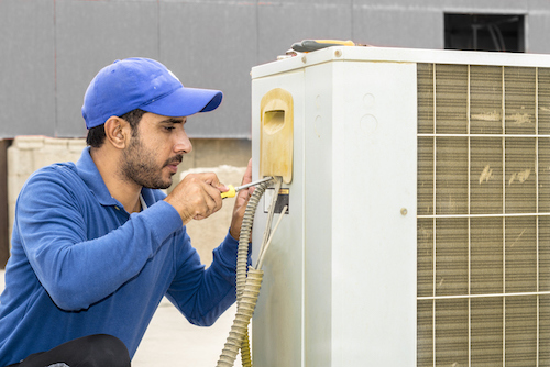 Local professional repairing an AC unit outside.