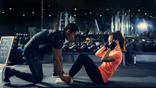 A local professional trainer helping a client exercise