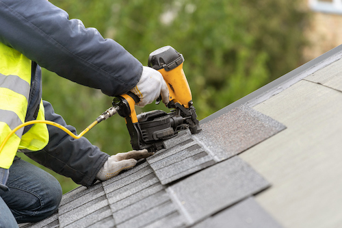 A local roofing employee installing shingles on a home.